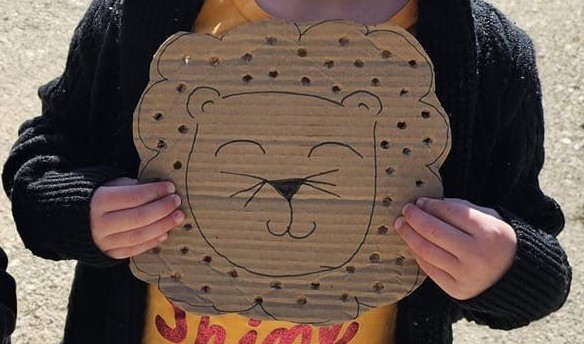 cardboard with lion drawing and holes punched into it. 